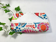 Load image into Gallery viewer, Cotton dispenser box in a brightly coloured pattern with 12 White cotton handkerchiefs folded inside