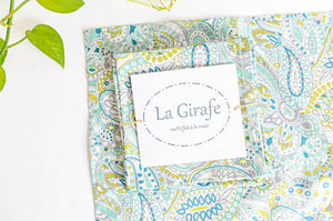 One Green Paisley napkin folded in a square on top of a flat a Green Paisley napkin