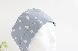 Close up of Cloth scrub hat with White Flamingo pattern on light Grey ground