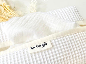 Closeup of a White tissue dispenser box made of waffle cotton showing a patch printed with La Girafe