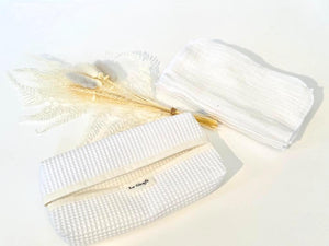 A White tissue dispenser box made of waffle cotton with a stack of white cotton hankies