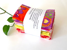 Charger l'image dans la galerie, A stack of folded towels with Plaids, Circles and Floral patterns in Pink, Orange, Yellow and Green