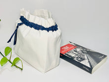Charger l'image dans la galerie, One big bag in off-white cotton canvas with a Blue Denim trim next to a book