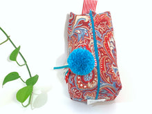 Load image into Gallery viewer, Top view of rectangular cloth cosmetic bag with zipper, Red Paisley pattern and Blue Pompon