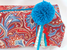 Load image into Gallery viewer, Closeup view of rectangular cloth cosmetic bag with zipper, Red Paisley pattern and Blue Pompon