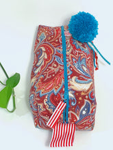 Load image into Gallery viewer, Top front view of rectangular cloth cosmetic bag with zipper, Red Paisley pattern and Blue Pompon