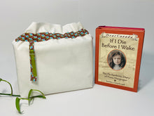 Load image into Gallery viewer, One big bag in off-white cotton canvas with a Peacock trim next to a book