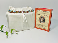 Load image into Gallery viewer, One big bag in off-white cotton canvas with a Peacock trim next to a book