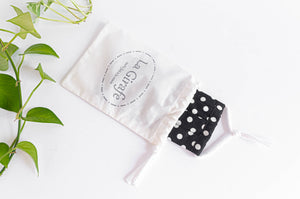 Ivory cotton cloth pouch with printed logo stating 100% hand made and containing one folded mask