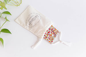Ivory pouch printed with La Girafe logo and containing one folded face mask