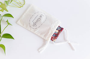 Ivory cotton pouch with printed logo stating 100% hand made  and with face mask inside