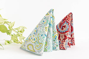 One Red Paisley Napkin and one Green Paisley Napkin folded in a triangle