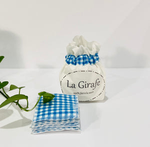 Ivory pouch printed with La Girafe Couture logo with a stack of Blue Checkered makeup remover pads