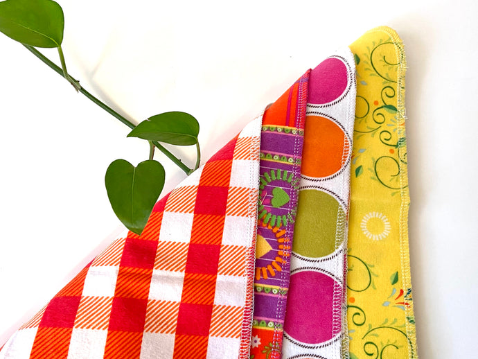 Four flat towels with Plaids, Circles and Floral patterns in bright Pink, Orange, Yellow and Green