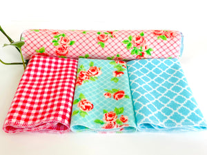 Three folded and one rolled towels with Roses and Checks patterns in Blue and Pink