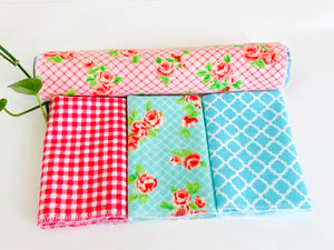 Three folded and one rolled towels with Roses and Checks patterns in Blue and Pink