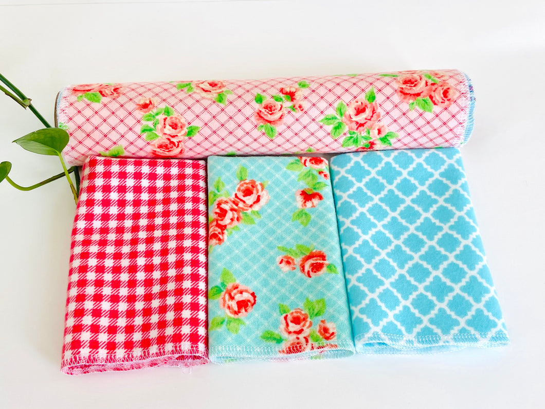 Three folded and one rolled towels with Roses and Checks patterns in Blue and Pink