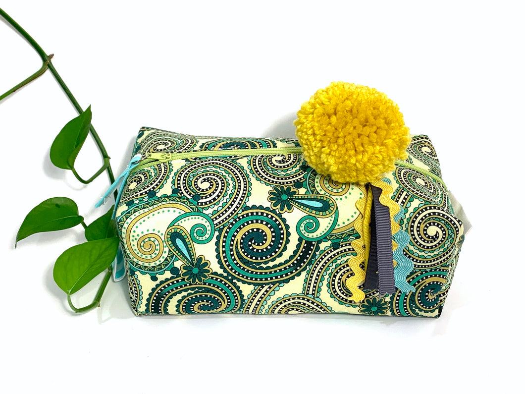 Side view of rectangular Cosmetic bag with Green Paisley printed pattern and Yellow Pompon