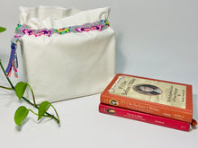Charger l&#39;image dans la galerie, One big bag in off-white cotton canvas with a Butterfly trim next to a book
