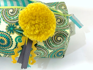 Closeup of rectangular Cosmetic bag with Green Paisley printed pattern and Yellow Pompon