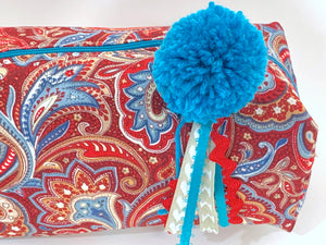 Closeup view of rectangular cloth cosmetic bag with zipper, Red Paisley pattern and Blue Pompon