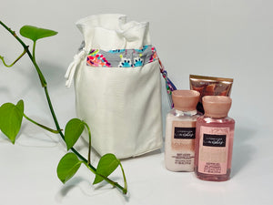 One small bag in off-white cotton canvas with a Butterfly trim next to 3 small bottles of lotion