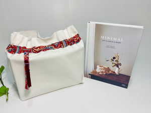 One big bag in off-white cotton canvas with a Red Paisley trim next to a book