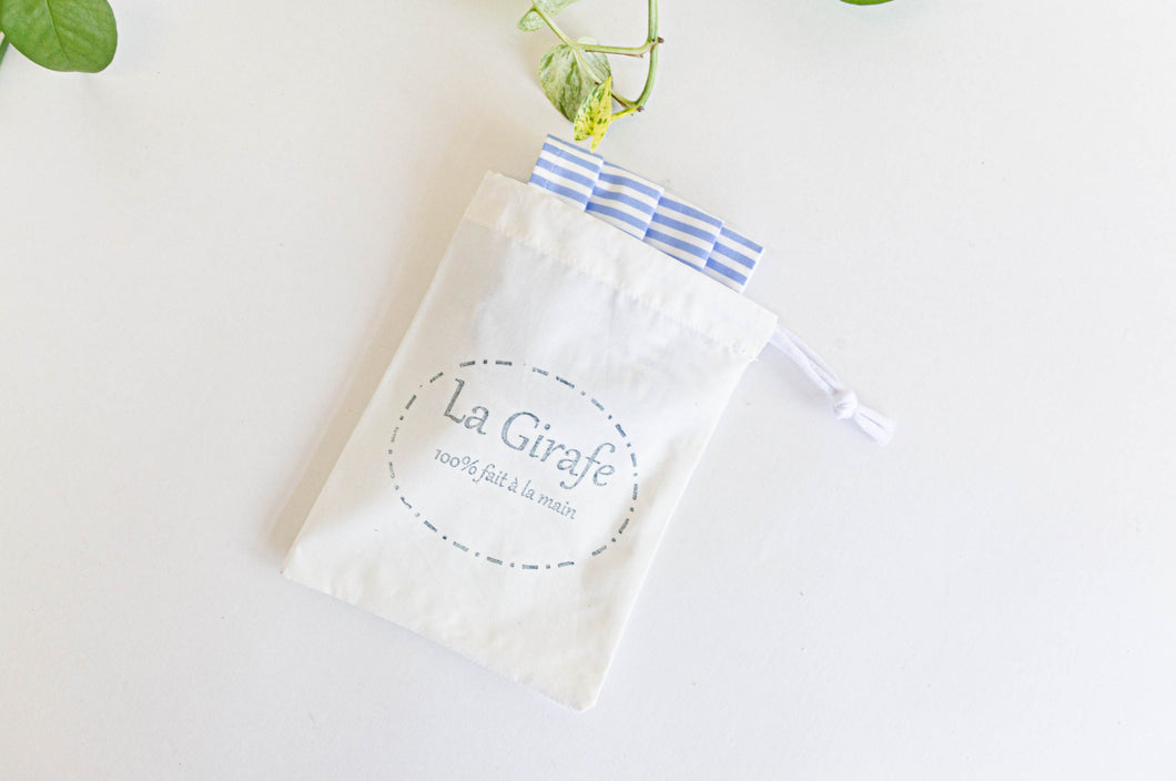 Ivory pouch printed with La Girafe logo and containing one folded face mask