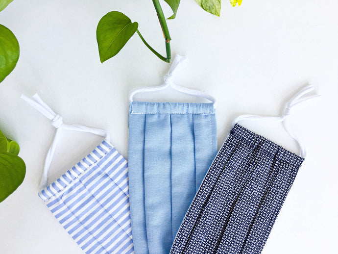 Closeup of Three face masks one with Blue & White Stripes, one in Plain Blue and One with Navy print